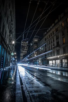 夜晚的城市街道充满活力，灯光长时间照射在潮湿的路面上，留下斑驳的痕迹