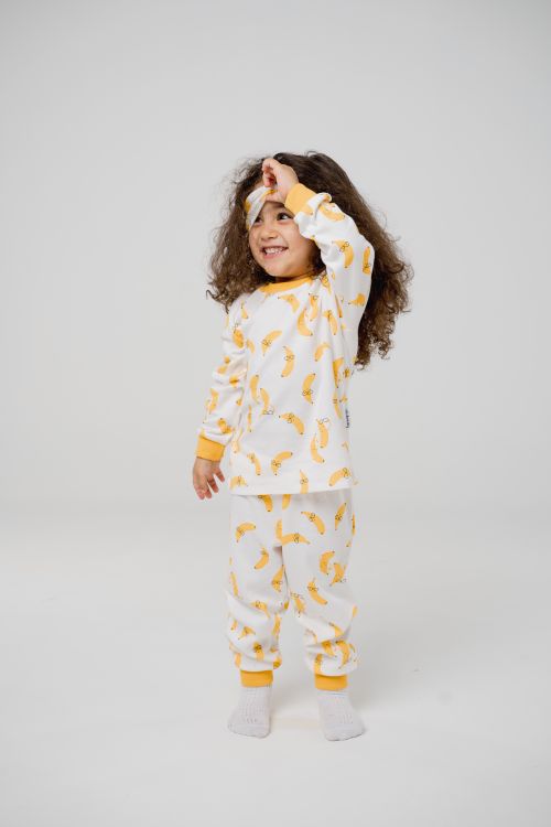 Free Adorable child in banana print pajamas poses joyfully in a studio setting. Stock Photo