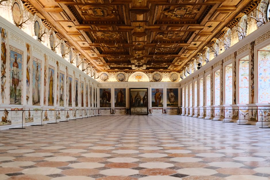 Luxurious palace hall in Innsbruck featuring historical paintings and intricate decor.