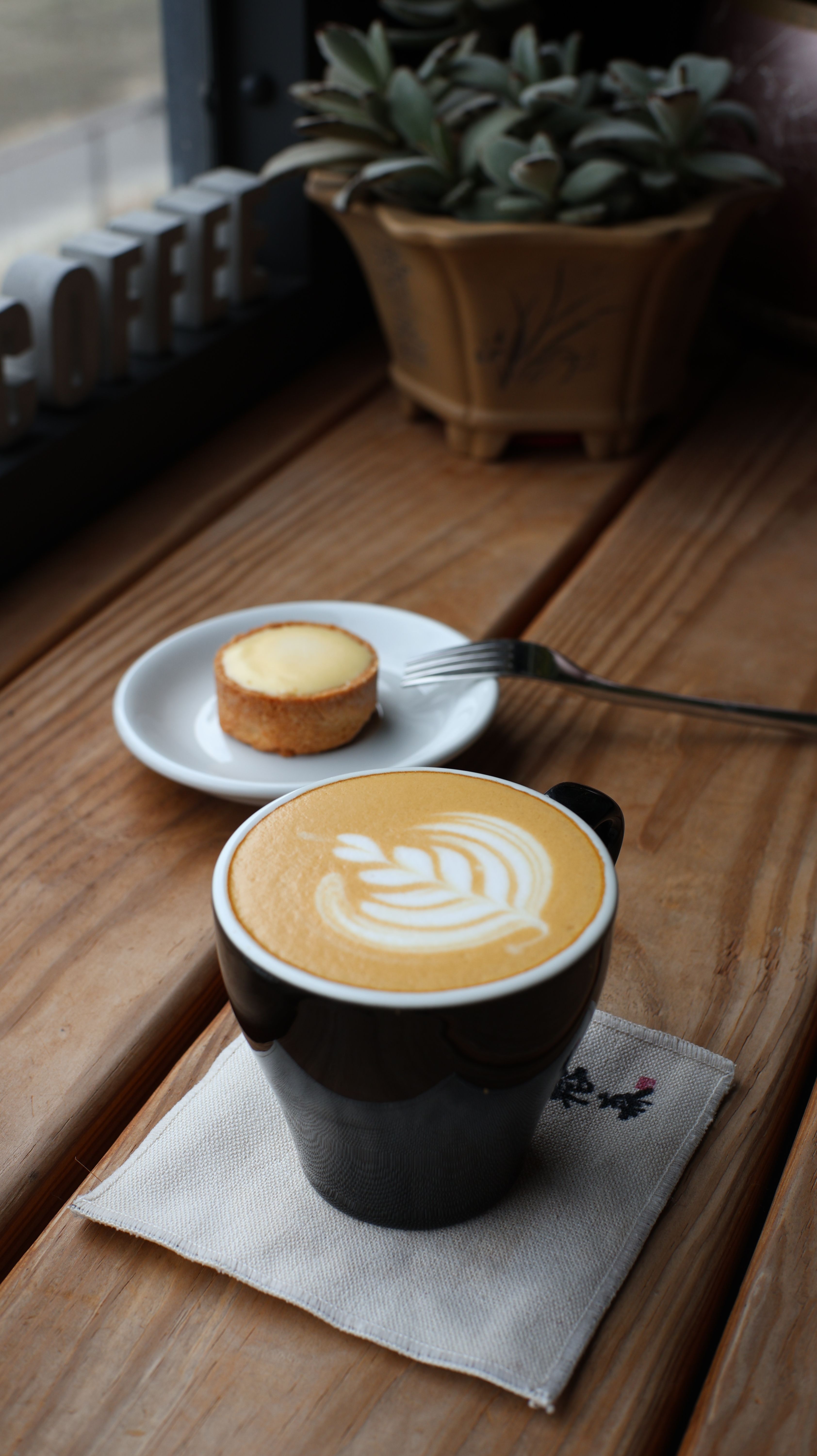 Warm cafe scene with latte art and pastry on wooden table, perfect for cozy lifestyle themes.