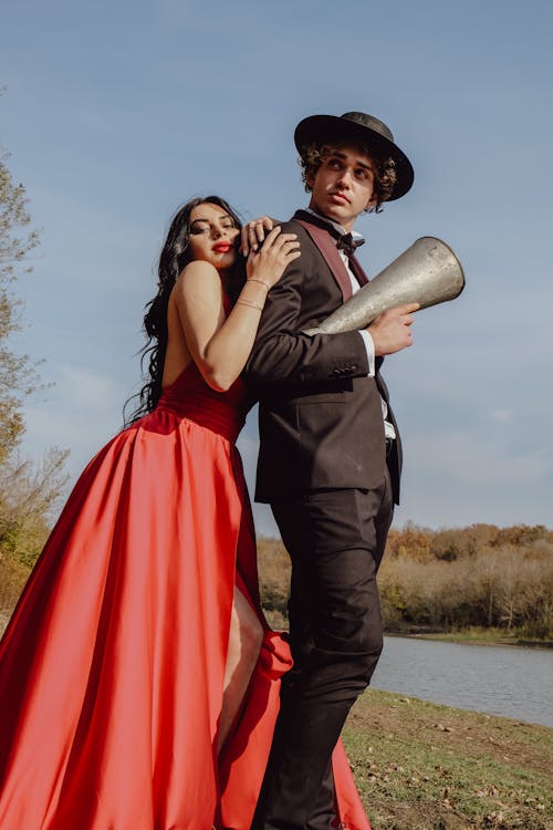 Young Woman Wearing a Red Evening Gown Leaning on a Man Holding an Old-Fashioned Megaphone