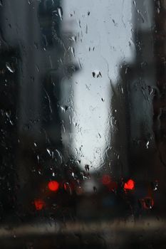 A rainy urban scene with raindrops on a window overlooking Toronto's cityscape. Moody and atmospheric.