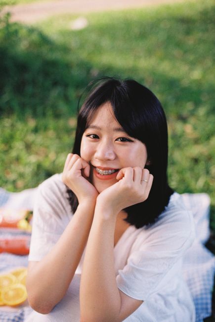 Young woman smiling and enjoying a relaxing picnic outdoors on a sunny day.