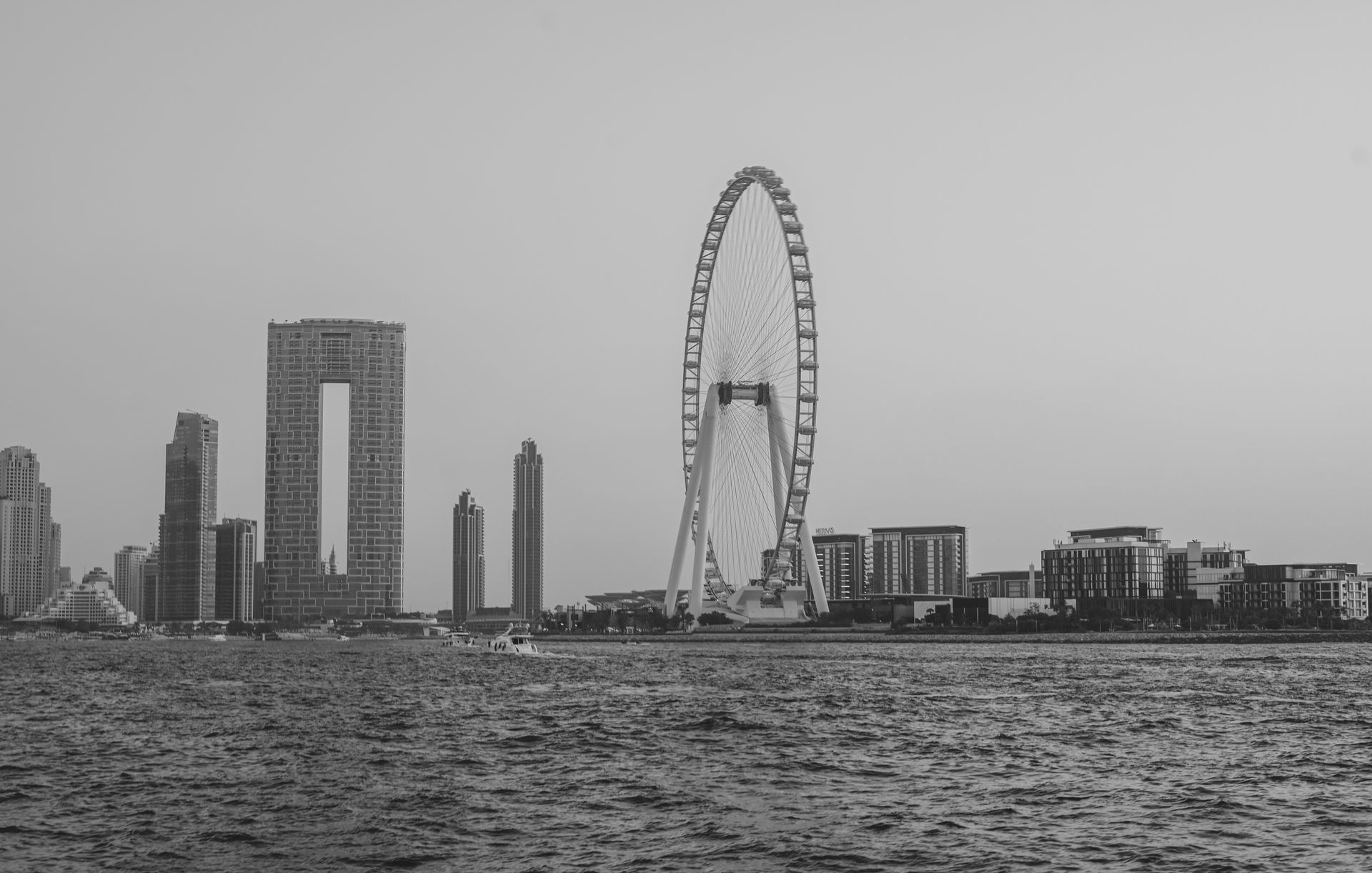 Scenic view of Dubai skyline featuring iconic Ferris wheel and urban architecture in black and white.