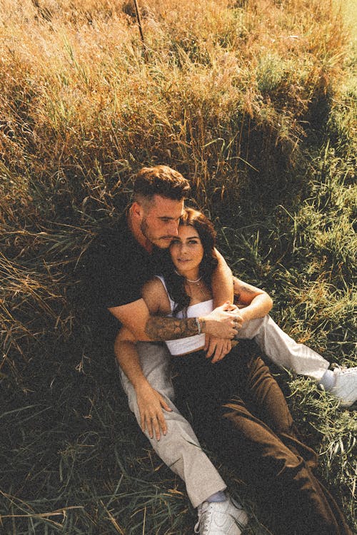 Couple Sitting on Field and Hugging