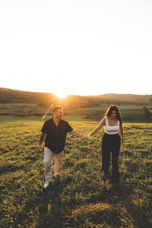 Couple Walking on Grassland at Sunset