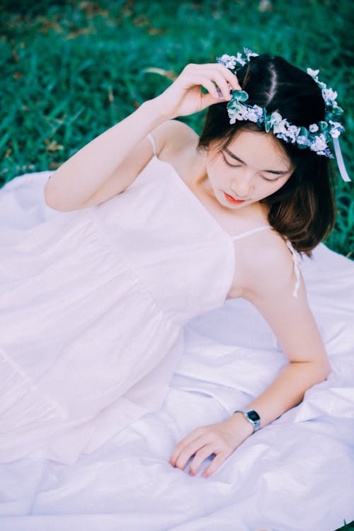Woman in Flowers Wreath and White Dress Lying Down on Picnic