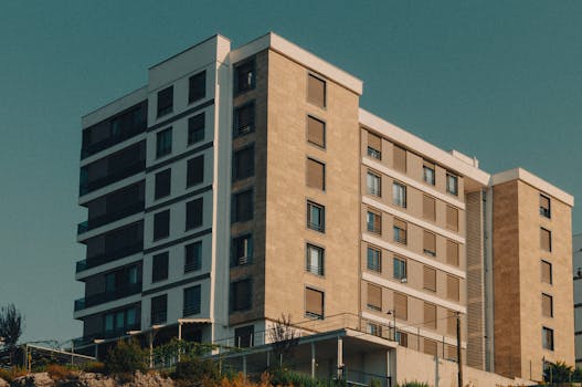 A modern apartment building with beige facade against a clear sky.
