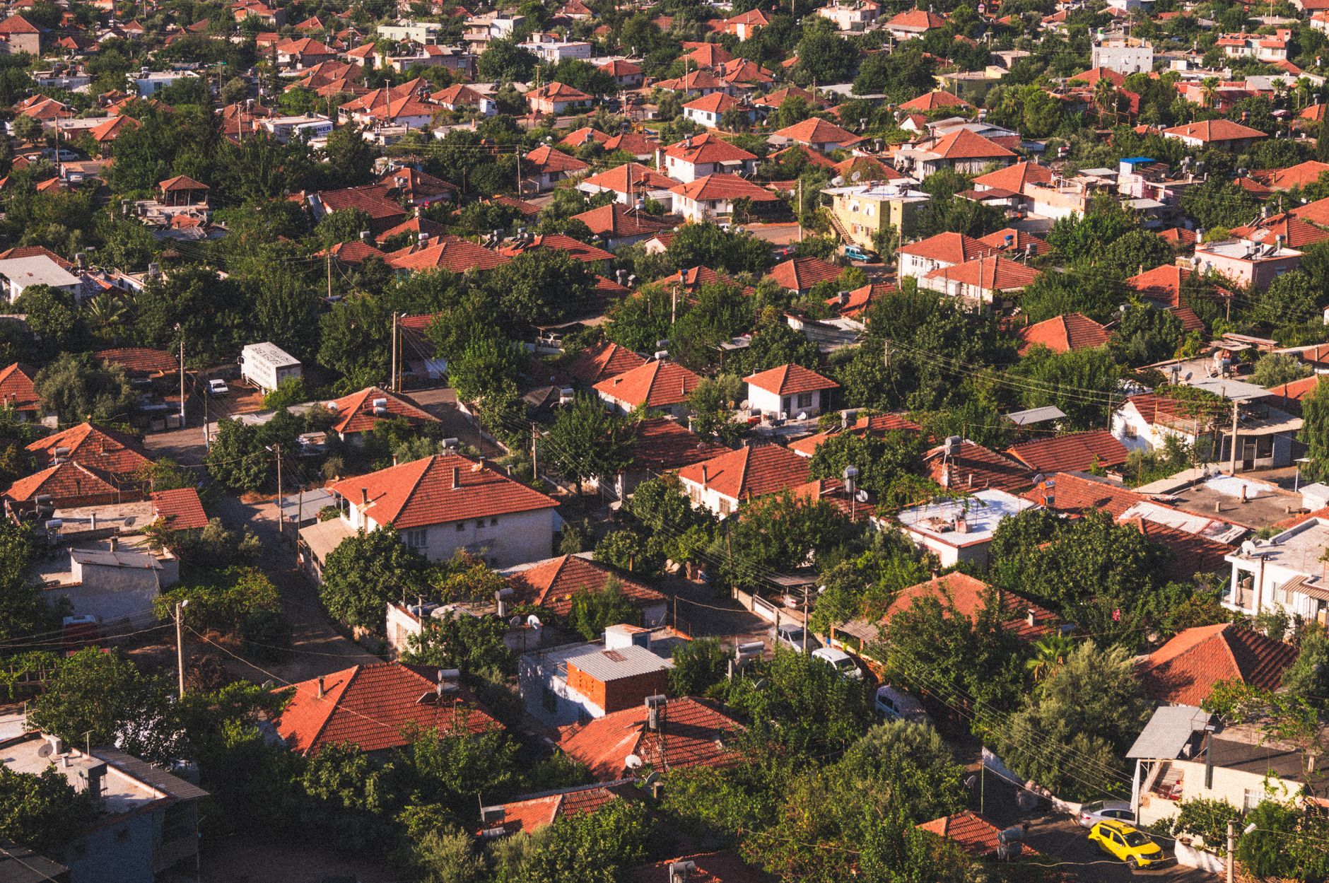 Vibrant aerial view of a suburban neighborhood with red-tiled roofs surrounded by lush greenery.