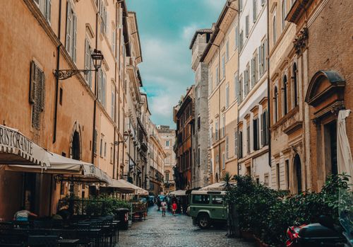 Free A picturesque cobblestone street in Rome with outdoor cafes and historic architecture. Stock Photo