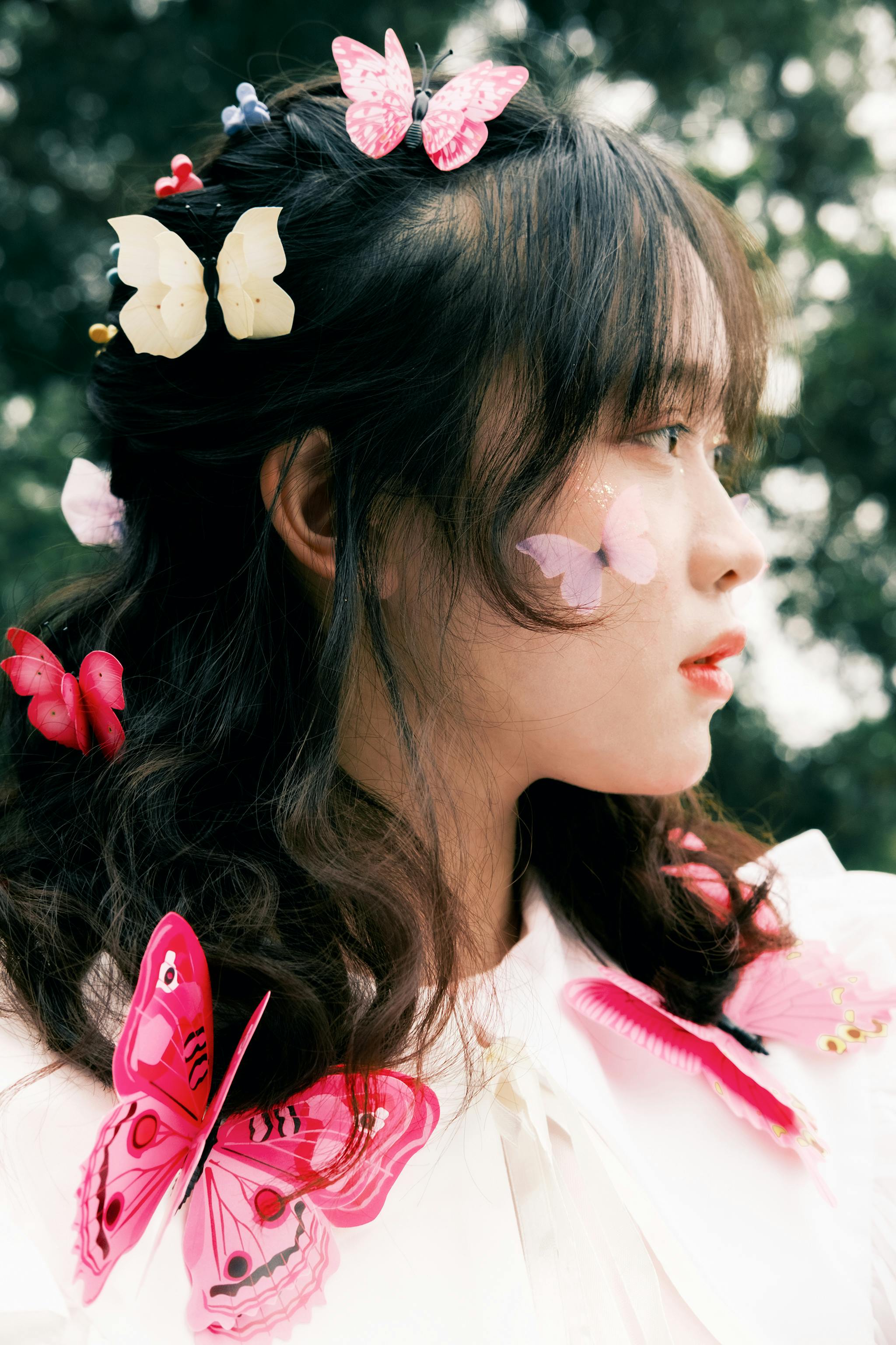 A young woman adorned with colorful butterfly clips in her hair, gazing thoughtfully outdoors.