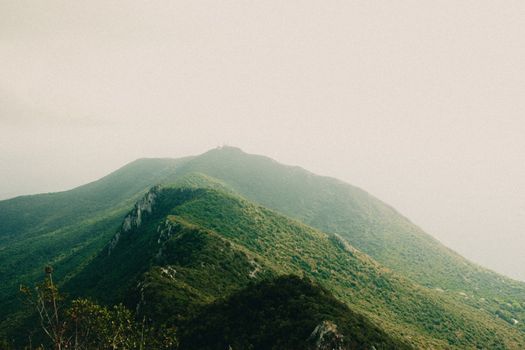 A scenic view of a verdant mountain range beneath cloudy skies, showcasing natural beauty.