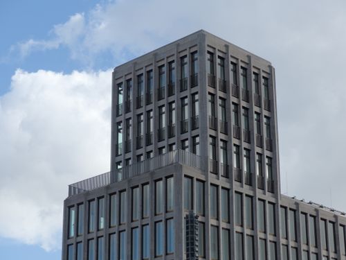 Free A sleek modern skyscraper with large windows framing its facade under a cloudy sky. Stock Photo