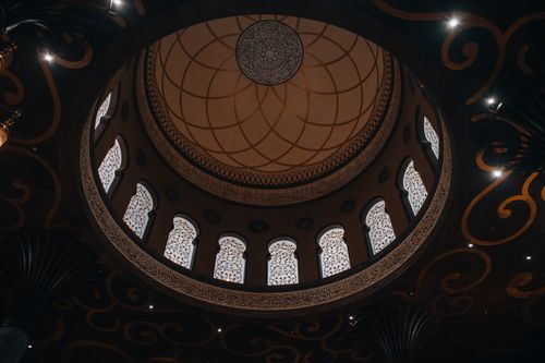 Free A stunning view of an ornate mosque dome with intricate Arabic patterns and windows. Stock Photo