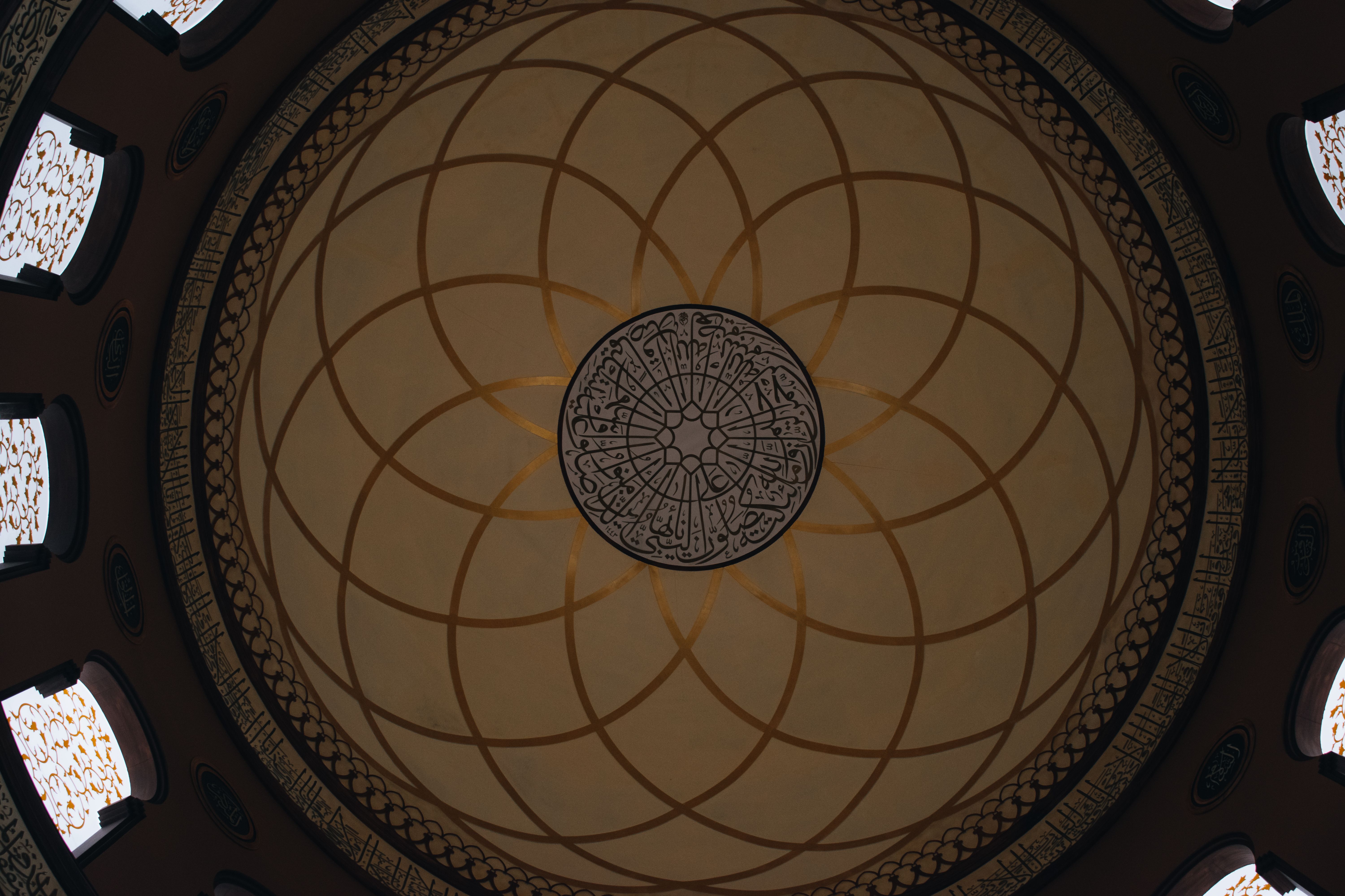 Ornate dome ceiling featuring Islamic art and geometric patterns in a mosque interior.