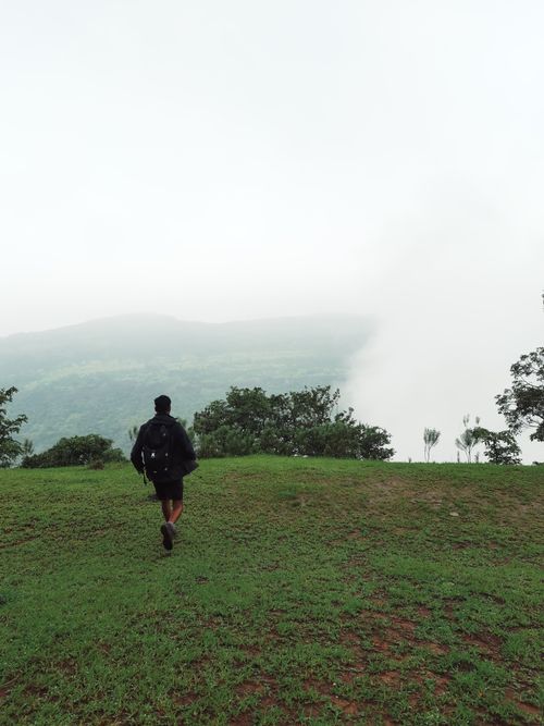Free Solo hiker with backpack exploring a lush, foggy hilltop landscape. Stock Photo