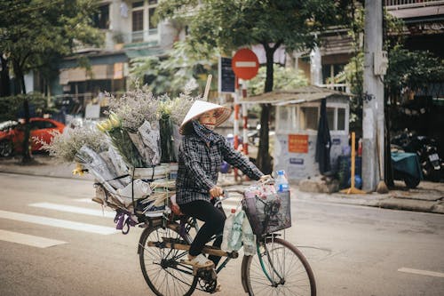 彼女の自転車の荷物ラックに花と自転車に乗る女性