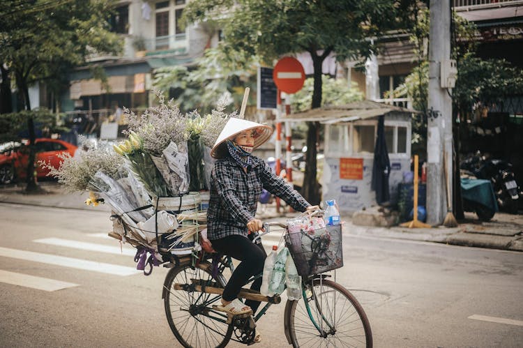 Woman Riding On Bike With Flowers On Her Bicycle Luggage Rack