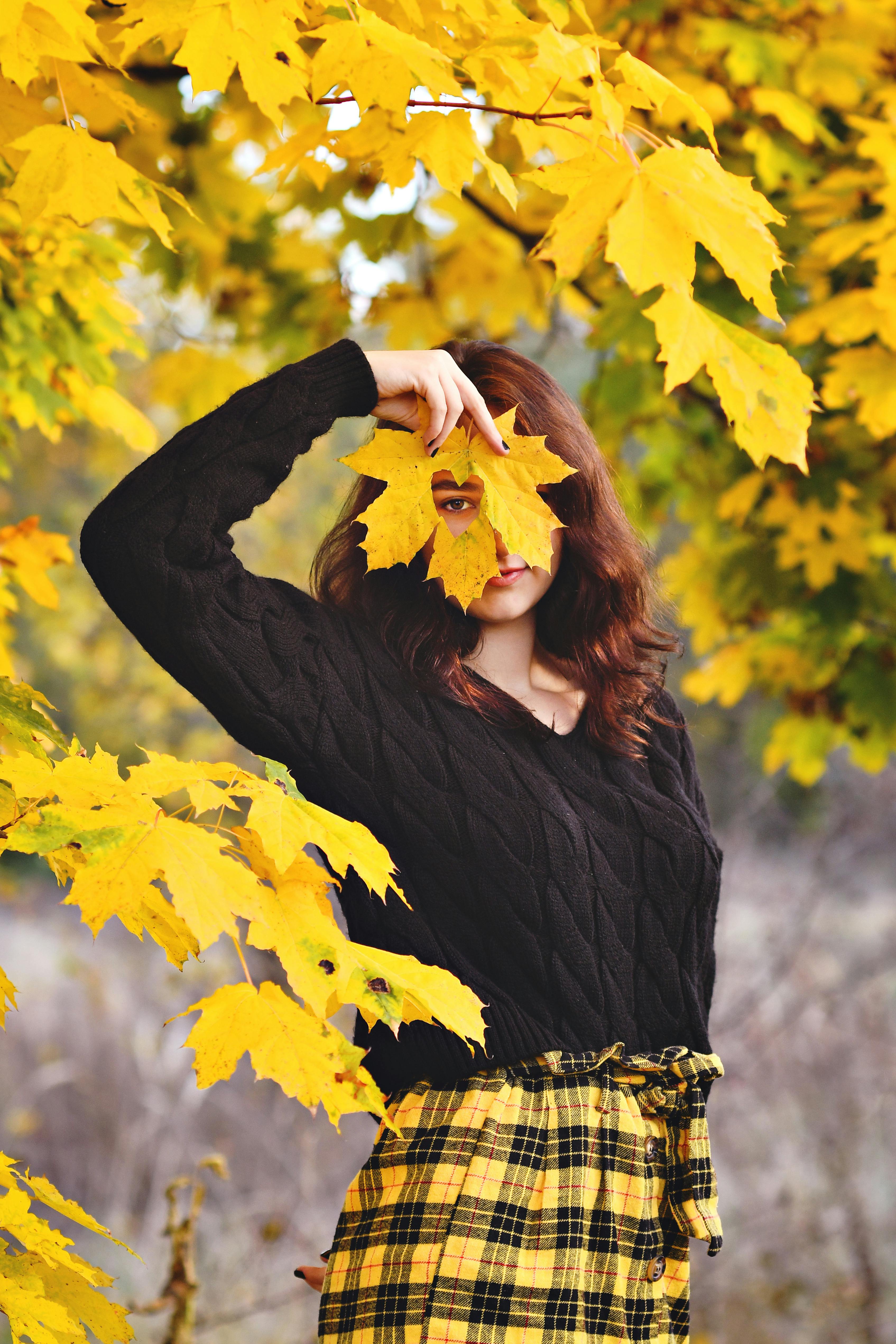 woman posing among yellow autumnal leaves