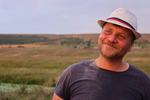Happy Man Wearing a Hat Standing on a Field 