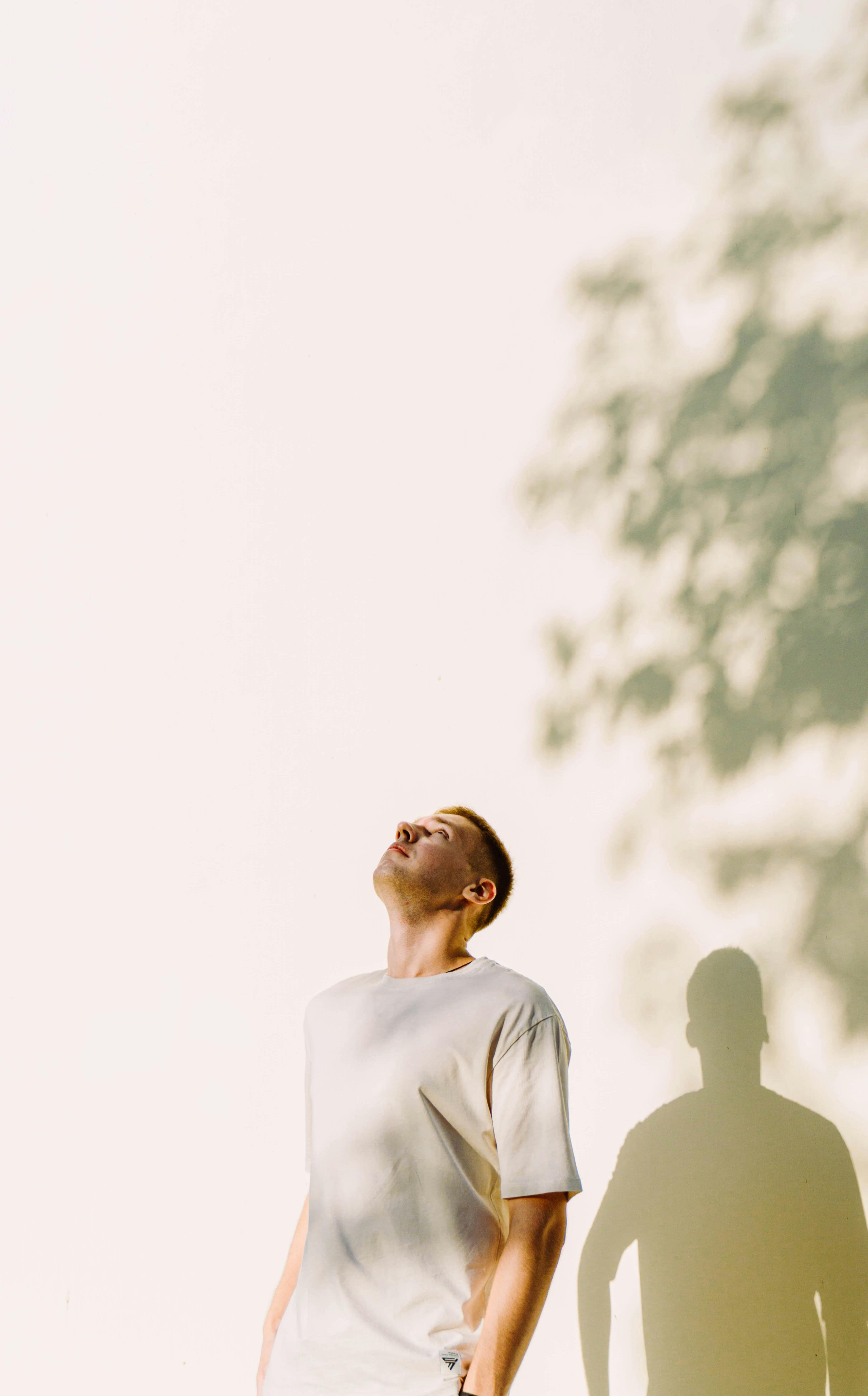 a portrait of a young boy looking up with his hands in his pockets at a summer sunset