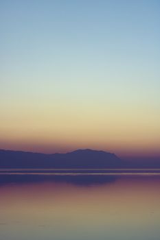 Tranquil twilight scene with mountain silhouette reflected in a calm lake, perfect for nature themes.