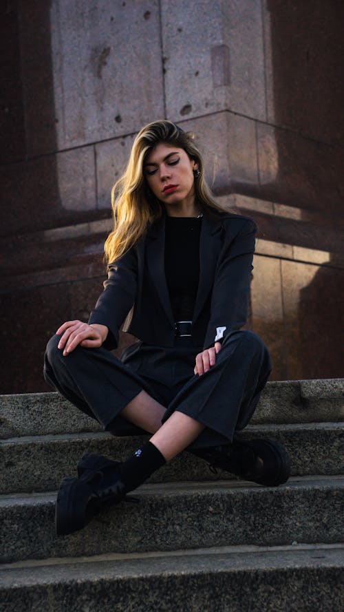Model in a Short Gray Blazer and Crease Pants Sitting Cross-legged on the Steps