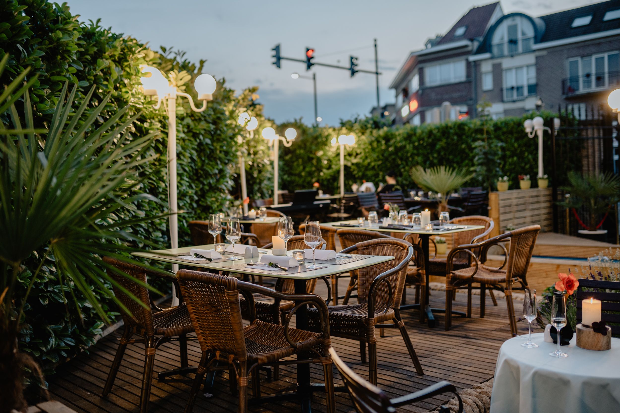 Cozy outdoor restaurant terrace with empty tables and warm lighting during dusk.