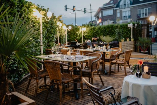 Charming restaurant terrace with wicker chairs and glowing lights, perfect for a relaxed evening.