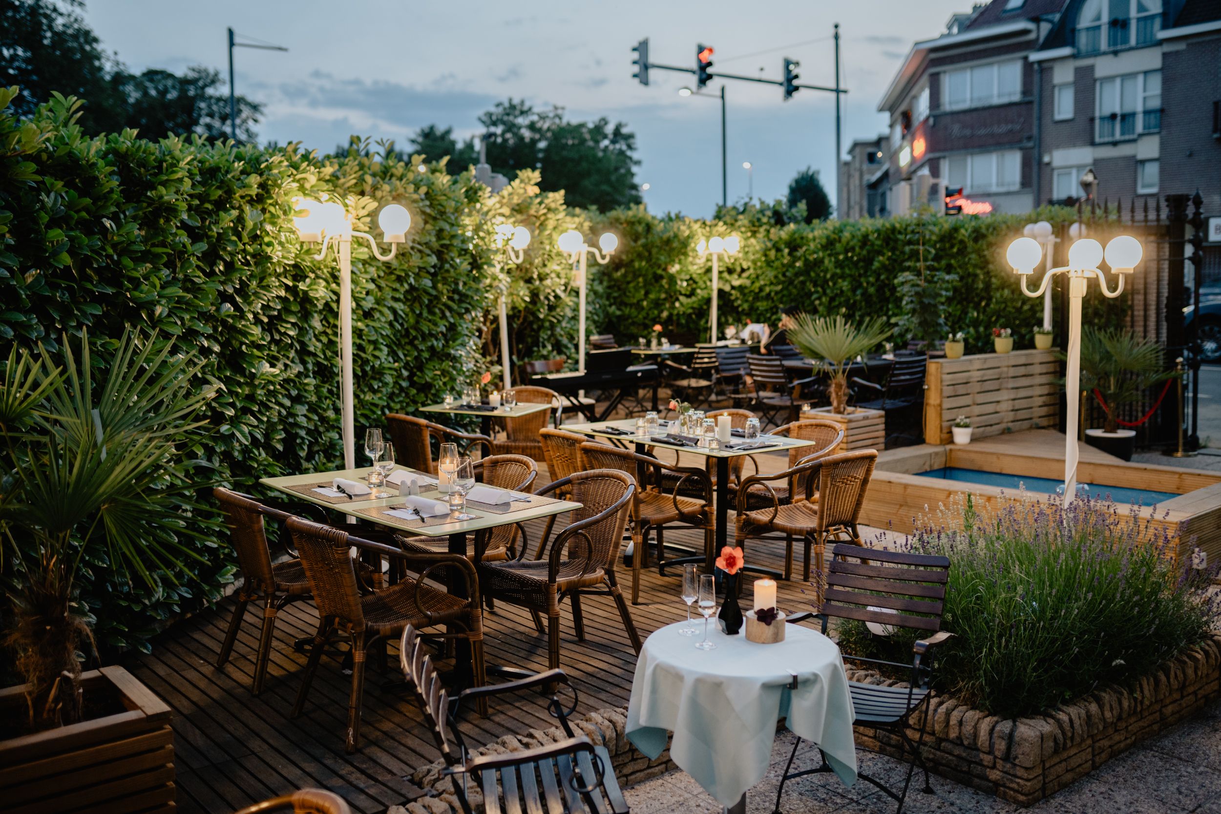 Inviting outdoor restaurant seating area with elegant lamps and lush greenery.