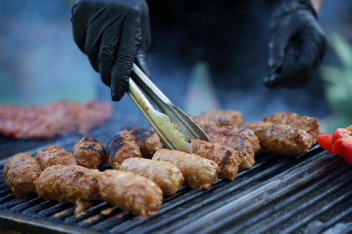Close-up of a Person Turning the Meat on a Grill Grid 