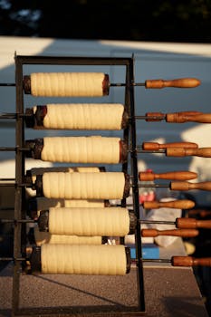 Freshly made Hungarian chimney cakes on a rotisserie, capturing the baking process outdoors.