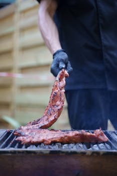 Close-up of succulent ribs cooking on an outdoor grill, perfect for summer BBQ gatherings.