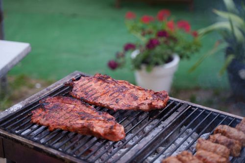 Free Juicy ribs sizzling on a charcoal grill in a garden setting. Perfect for summer BBQs. Stock Photo