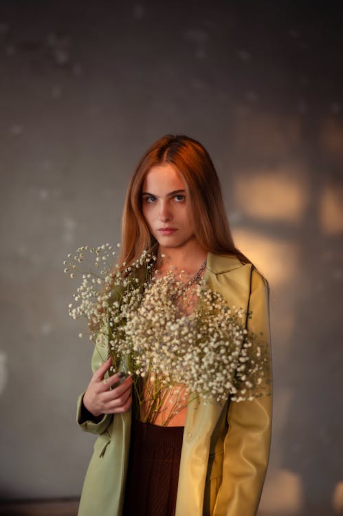 Model in a Green Imitation Leather Coat with Flowers Tucked into the Waistband of her Skirt