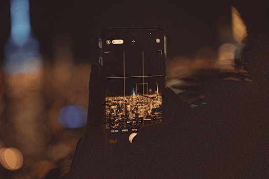 A smartphone captures the vibrant New York City skyline in a night scene, focusing on city lights.