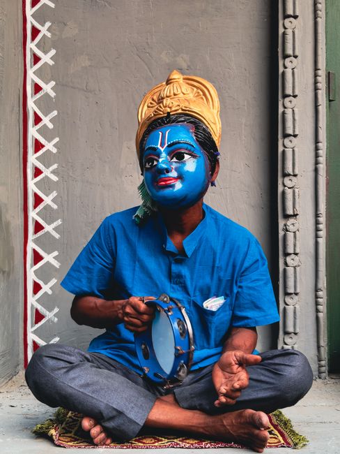 Colorful performance capturing a masked Indian man in traditional costume during a cultural festival.