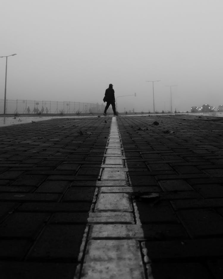 Pavement Of A Sidewalk With Line And Passerby On A Foggy Day