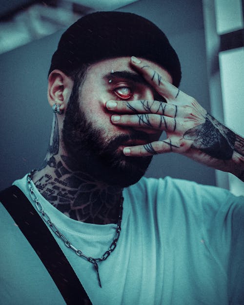 Portrait of Man with Tattoos and Fingers around Eye