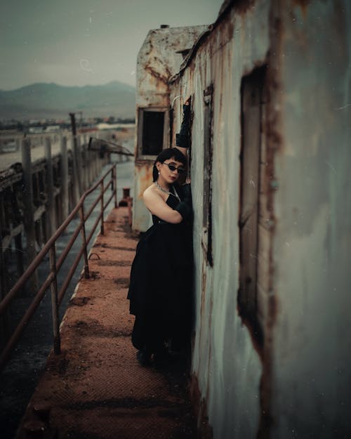 Woman in Black Dress Posing by Abandoned Building Wall