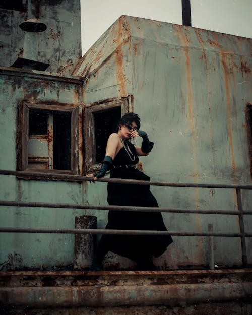 Woman in Black Dress Posing by Abandoned Building Wall