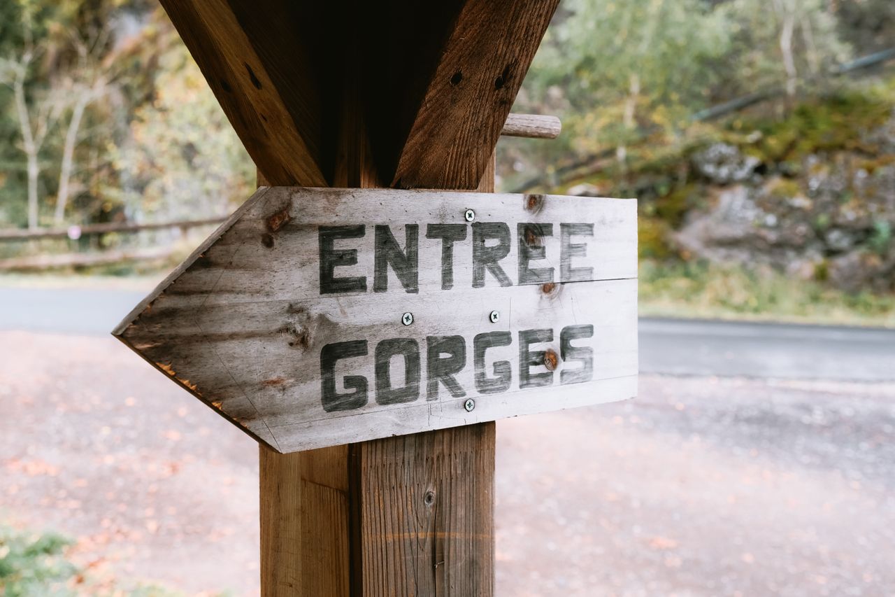 a wooden sign reading entree gorges outdoors indicating a gorge entran
