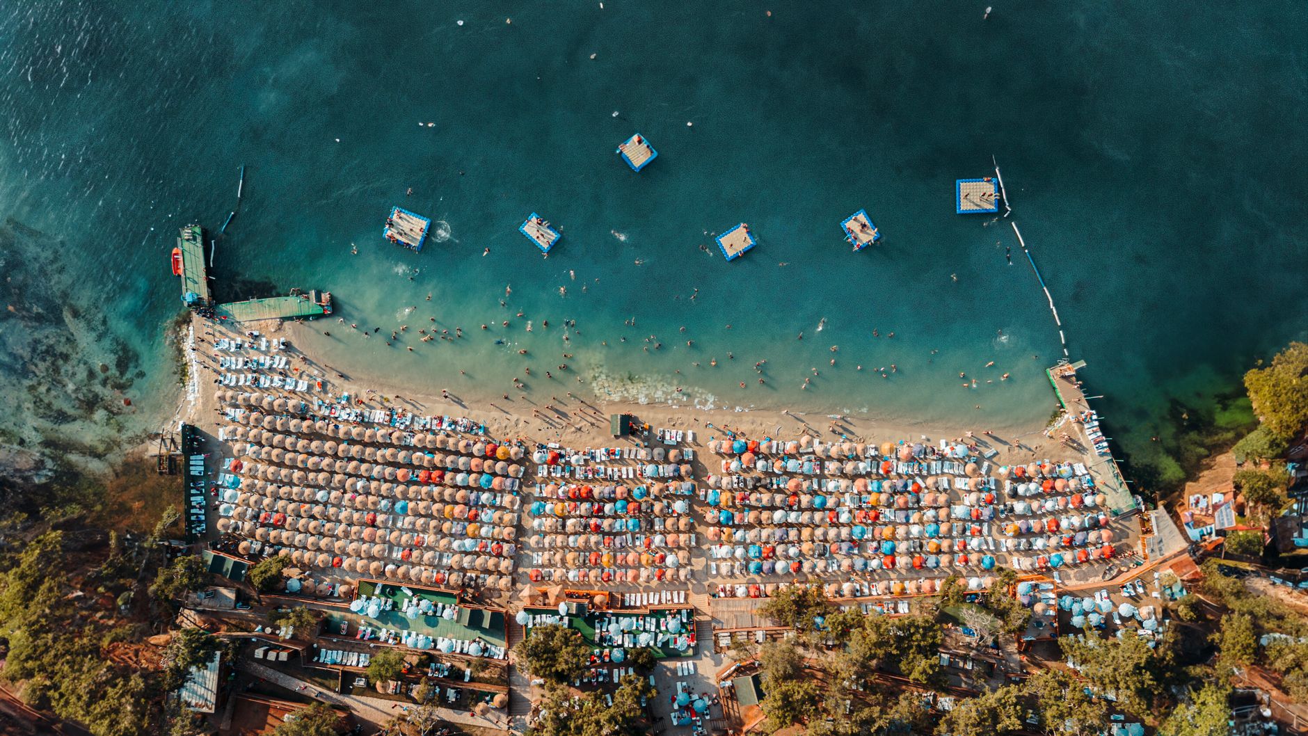 Stunning aerial view of Heybeliada beach with colorful umbrellas and turquoise waters.