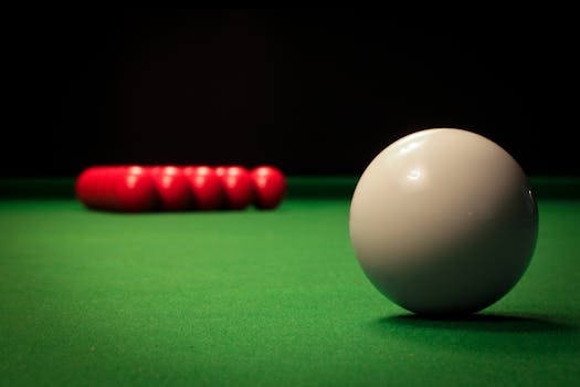 A detailed view of billiard balls on a snooker table with a focus on the white ball.