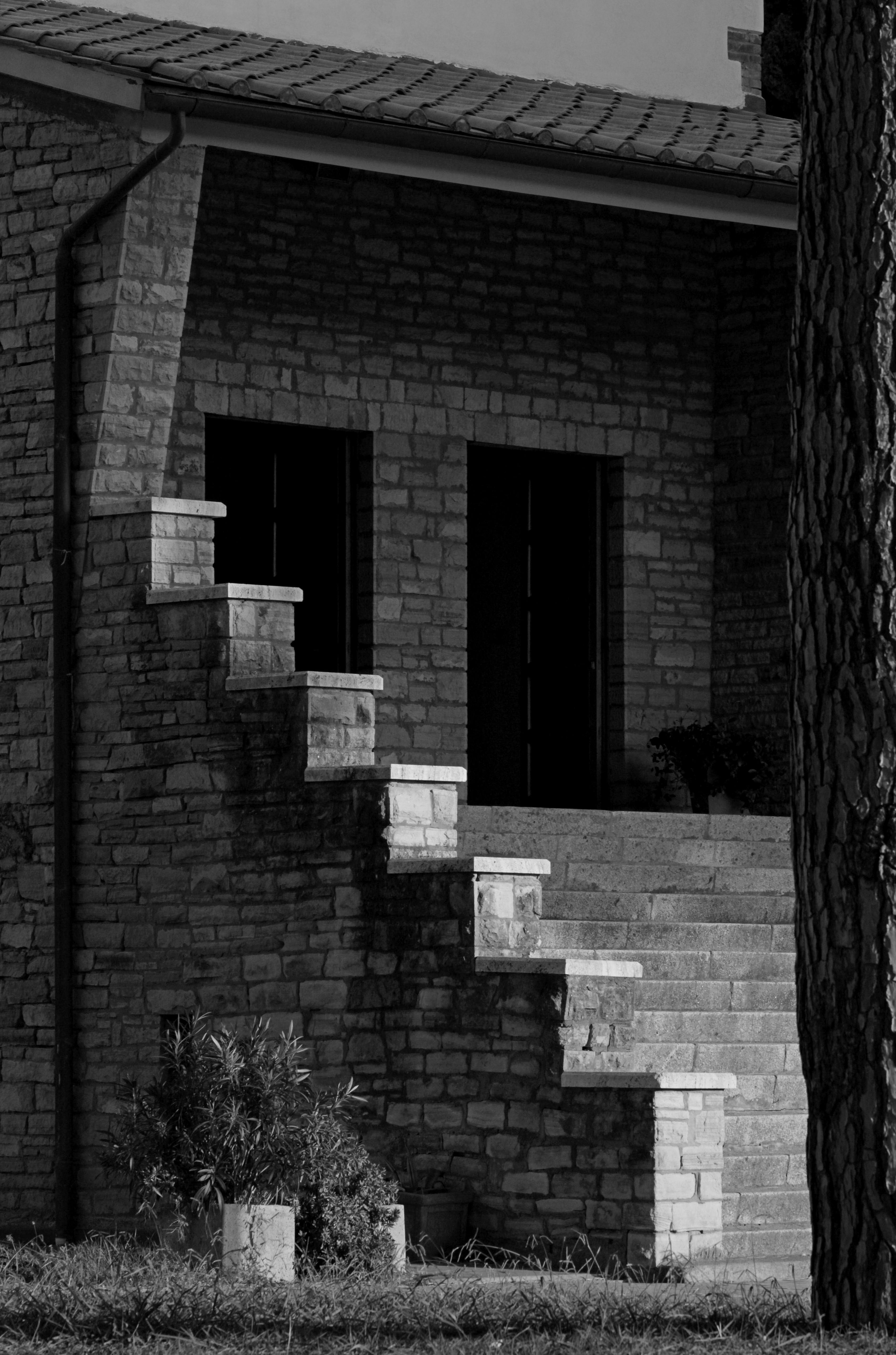 Monochrome image of a rustic brick stairway leading to a house entrance.
