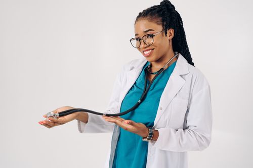 Free Smiling female doctor holding a stethoscope, wearing glasses and scrubs on a white background. Stock Photo