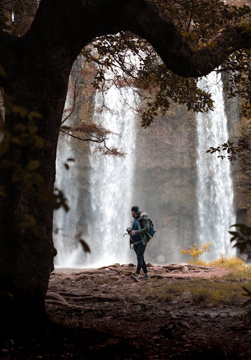Man Stands in Front of Falls in Fforest