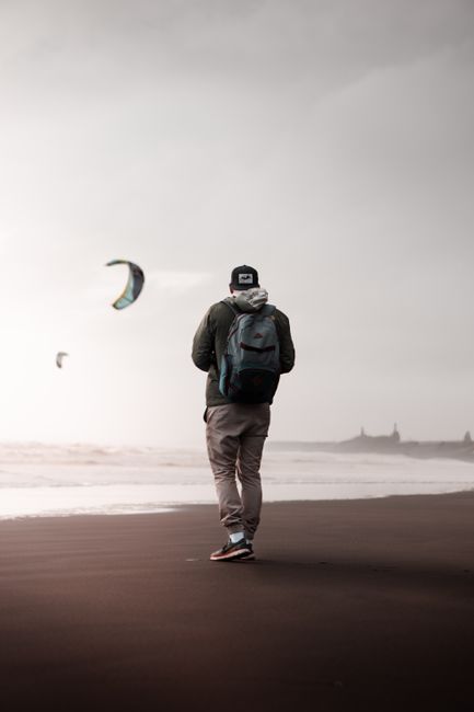 A man walking solo on Muriwai Beach, Auckland, capturing the essence of travel and adventure.