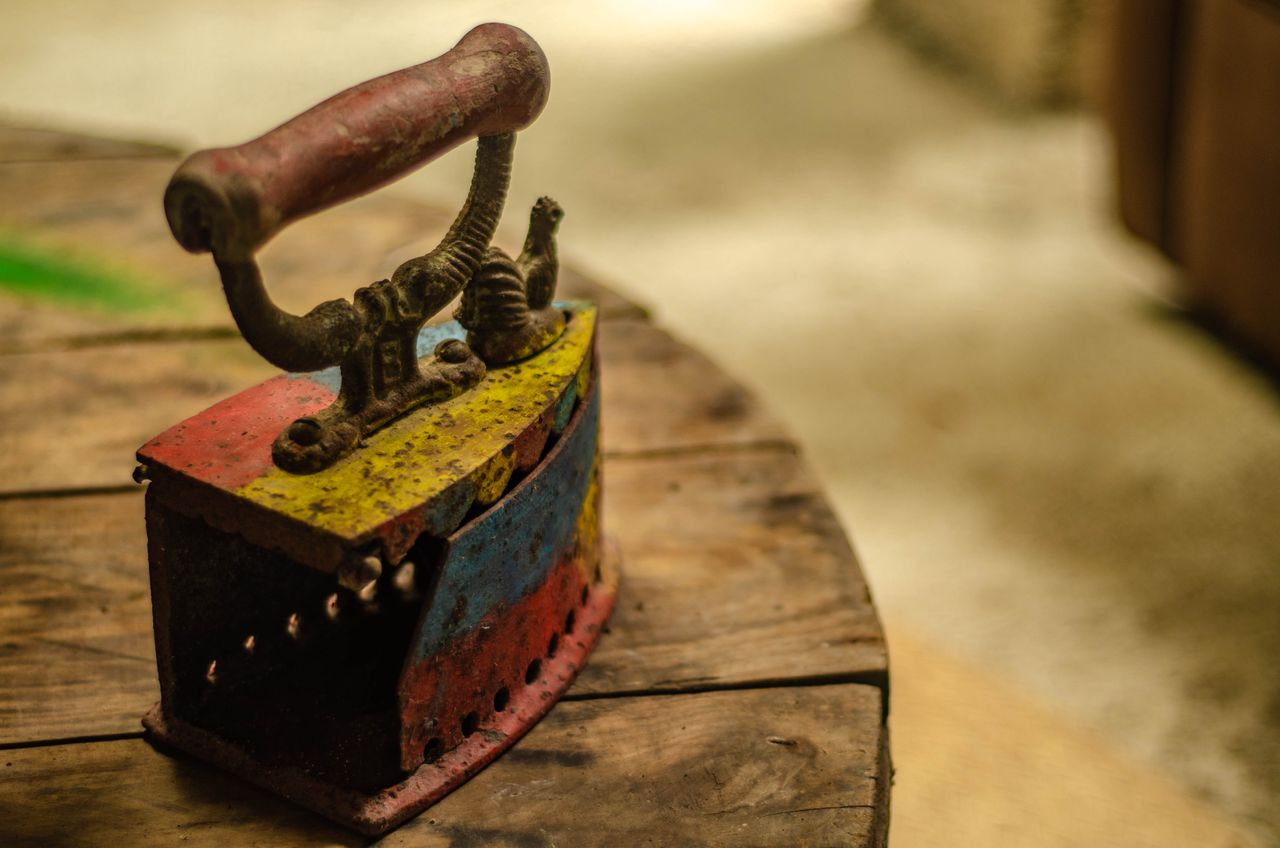 a close up of a colorful vintage iron placed on a rustic wooden table