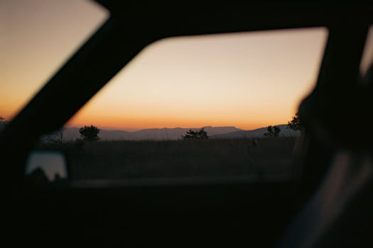 Peaceful sunset landscape seen through car window, perfect for travel themes.